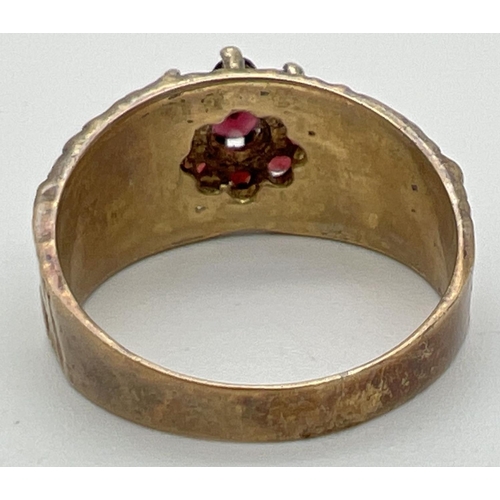 1023 - A vintage 9ct yellow gold ring with textured bark effect band set with a cluster of garnets in a flo... 