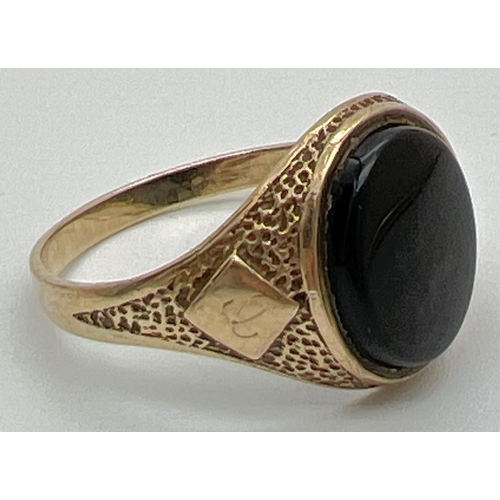 1025 - A mens 9ct gold vintage signet ring set with an oval black onyx stone. Pitted effect detail to shoul... 