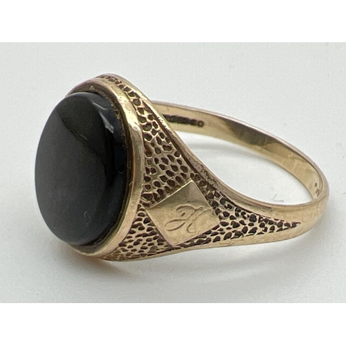 1025 - A mens 9ct gold vintage signet ring set with an oval black onyx stone. Pitted effect detail to shoul... 