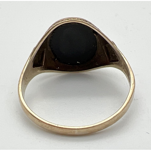 1025 - A mens 9ct gold vintage signet ring set with an oval black onyx stone. Pitted effect detail to shoul... 