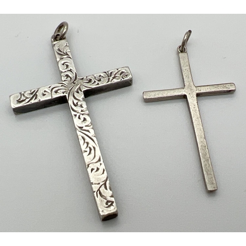 1005 - 2 silver cross pendants with hanging bales. One plain, the other with engraved decoration to front. ... 