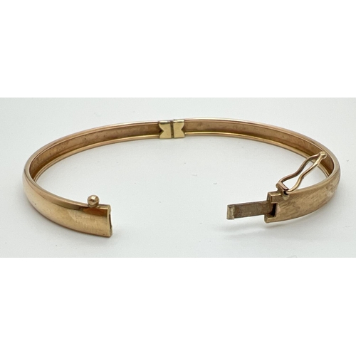 1037 - A vintage 9ct gold bangle with half floral engraving and safety clip (in need of attention) to clasp... 