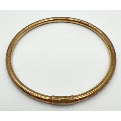 1045 - A vintage 9ct gold bangle with engraved floral pattern. Bangle has been repaired and strengthened wi... 