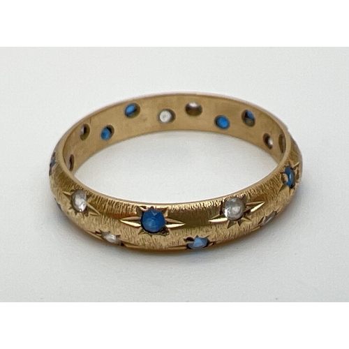 1088 - A 9ct gold band ring set with blue and clear stones. Design cut into ring around each stone to make ... 