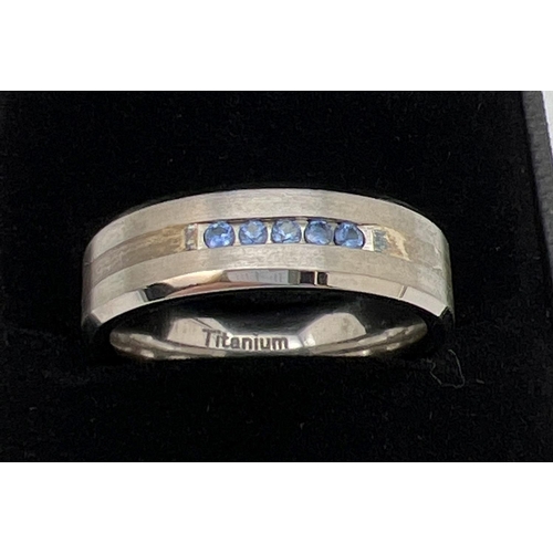 1089 - A brand new in box man's Titanium and Sapphire band ring. Two tone titanium with 5 round cut channel... 