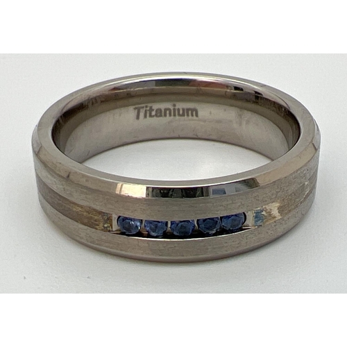 1089 - A brand new in box man's Titanium and Sapphire band ring. Two tone titanium with 5 round cut channel... 