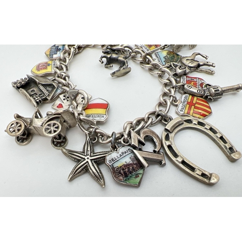 1099 - A vintage curb chain charm bracelet with 24 silver and white metal charms. To include a car, gun, ho... 