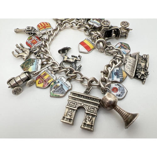 1099 - A vintage curb chain charm bracelet with 24 silver and white metal charms. To include a car, gun, ho... 