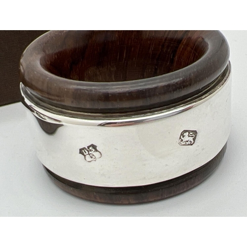 1144 - A boxed set of 4 dark wood napkin rings with hallmarked silver banded detail. Each approx. 4.5cm dia... 