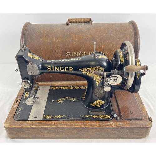 1304 - An antique wooden cased Singer sewing machine, black with gold floral decoration and shuttle bobbin.... 