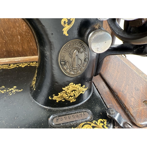 1304 - An antique wooden cased Singer sewing machine, black with gold floral decoration and shuttle bobbin.... 