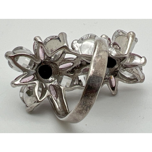 1031 - A large white metal double flower head design cocktail ring. Set with faceted black stones and check... 