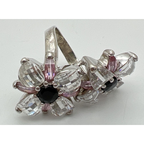 1031 - A large white metal double flower head design cocktail ring. Set with faceted black stones and check... 