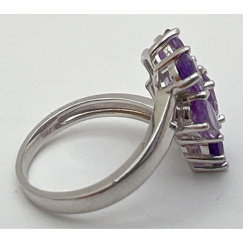 12 - A Genuine Gem Company silver and amethyst large dress ring. Set with 7 oval cut amethysts in a twist... 