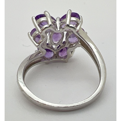 12 - A Genuine Gem Company silver and amethyst large dress ring. Set with 7 oval cut amethysts in a twist... 