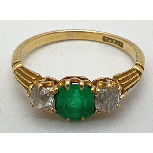 18 - A vintage 18ct gold, emerald and diamond trilogy ring with channelled design to shoulders. Central e... 