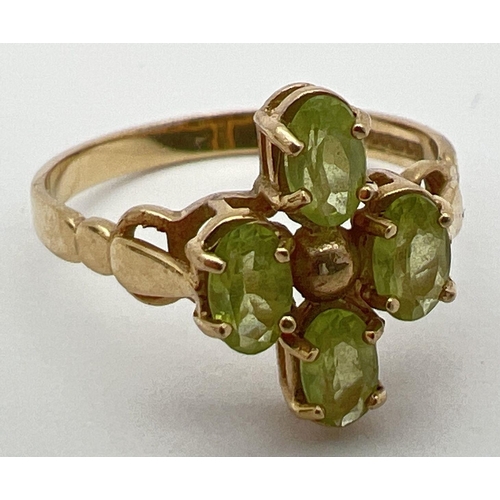 25 - A 9ct gold and peridot ring in a quatrefoil shaped setting with shaped shoulders. 4 oval cut peridot... 