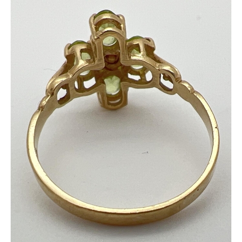 25 - A 9ct gold and peridot ring in a quatrefoil shaped setting with shaped shoulders. 4 oval cut peridot... 