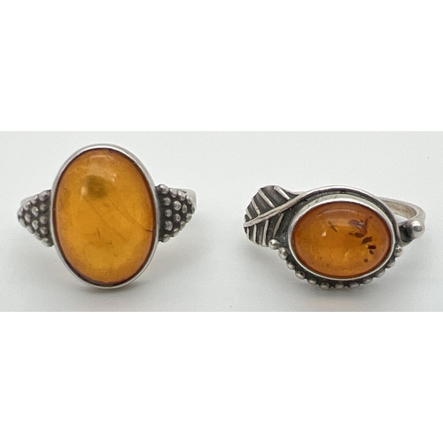 42 - 2 white metal amber set dress rings with decorative mounts, sizes O & P.