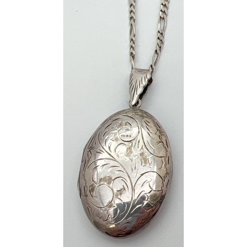 66 - A large vintage silver oval shaped locket with engraved foliate & scroll design. On an 18