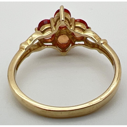 77 - A 9ct gold and orange sapphire ring with a quatrefoil shaped setting and open design shoulders. Full... 