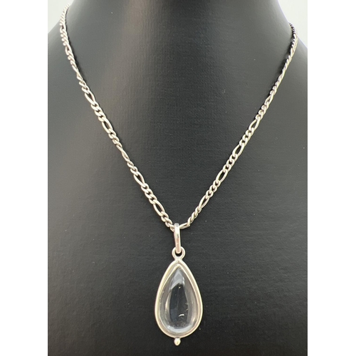 89 - A clear quartz teardrop shaped pendant in a white metal mount, on an 18