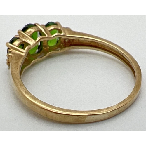 97 - A 9ct gold chrome diopside 3 stone trilogy ring, set with 2 small diamonds to each shoulder. Stamped... 