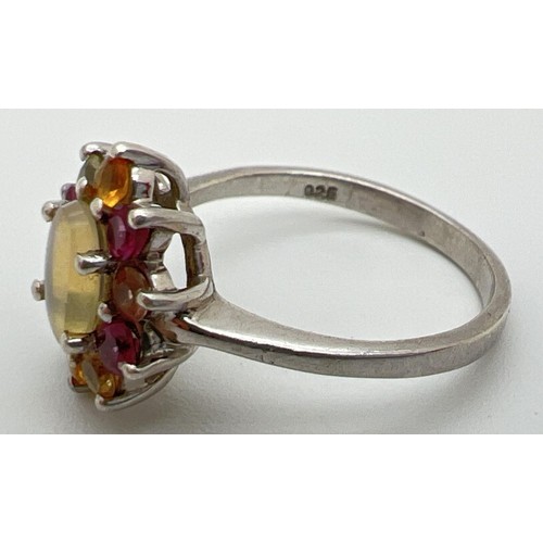 39 - A silver multi stone cluster ring set with oval shaped central opal surrounded by assorted coloured ... 