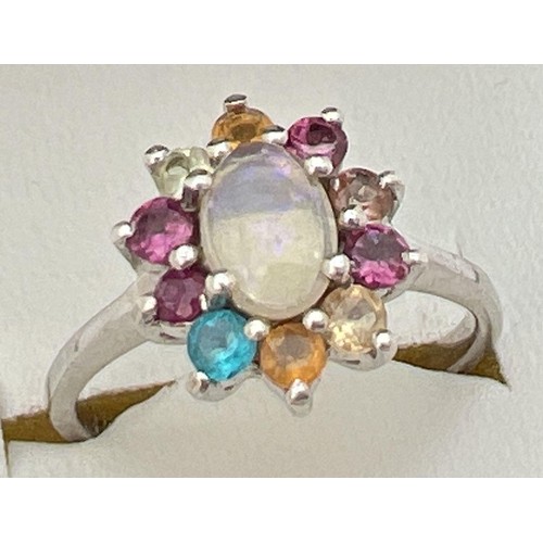 39 - A silver multi stone cluster ring set with oval shaped central opal surrounded by assorted coloured ... 