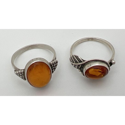 42 - 2 white metal amber set dress rings with decorative mounts, sizes O & P.