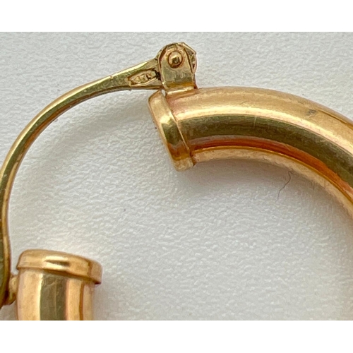 1006 - A pair of 9ct gold hollow hoop earrings with hinged posts, stamped 375. Approx. 3.2cm diameter, tota... 