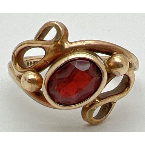 1005 - A 9ct gold and garnet contemporary design bespoke ring. Central oval cut garnet bezel set within a s... 