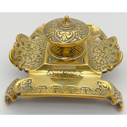 1158 - An antique brass inkwell with decorative scroll & foliate design to pen tray. Stamped '310' to under... 