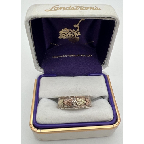 1061 - A boxed Landstrom Black Hills sterling silver and 12K rose & yellow gold band ring with floral and l... 