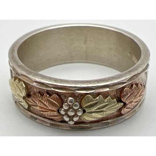 1061 - A boxed Landstrom Black Hills sterling silver and 12K rose & yellow gold band ring with floral and l... 