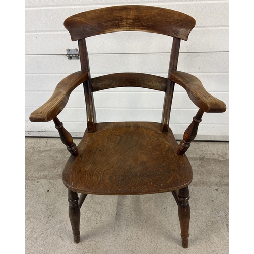 1398 - An antique elm wood, bar backed farmhouse kitchen arm chair. With turned detail to legs and arm supp... 