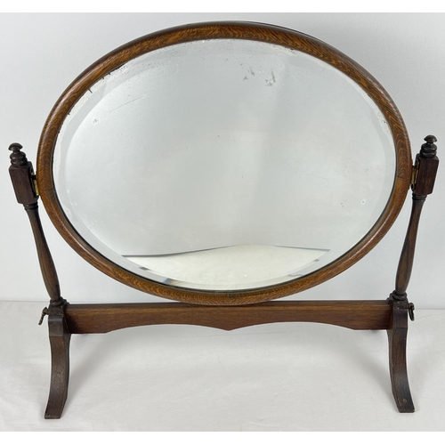 1399 - An antique dark wood framed, oval shaped, bevel edged swing mirror on stand. With brass fixings. App... 