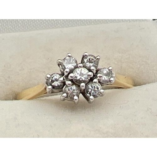 1090 - An 18ct gold and diamond ring set with 7 round cut diamonds in a flower shaped setting, totalling .3... 