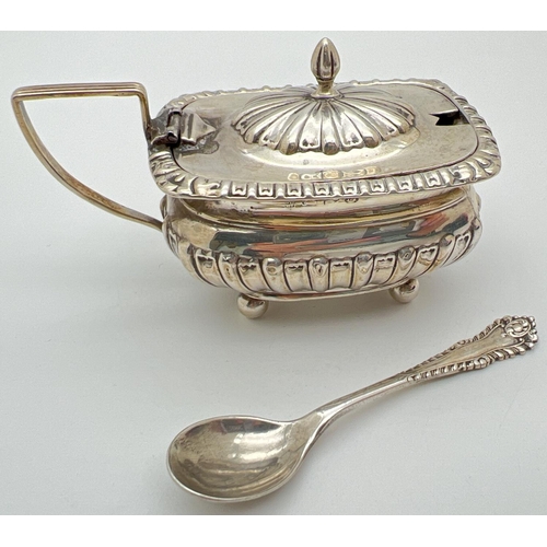 1129 - A Victorian silver mustard pot with blue glass liner and silver spoon. Pot raised on 4 ball feet wit... 