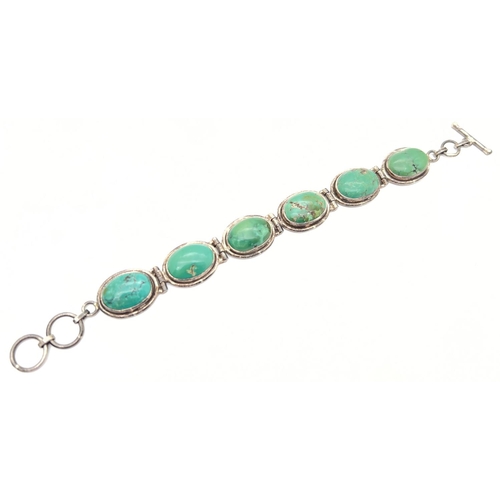 1011 - A six oval panel silver bracelet set with blue/green turquoise, with a t bar clasp. Silver marks to ... 