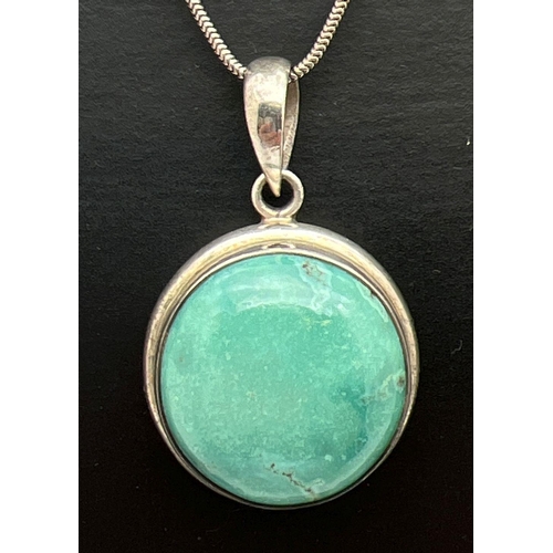 1042 - A silver circular pendant set with a cabochon of turquoise, on a 16