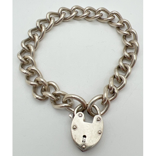 1045 - A heavy silver curb chain charm bracelet with padlock clasp. Silver mark to back of padlock. Total w... 