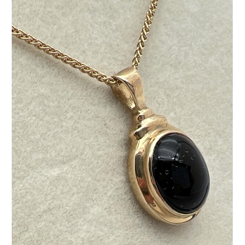 1050 - A boxed 9ct gold oval pendant set with a cabochon of black onyx. On an 18