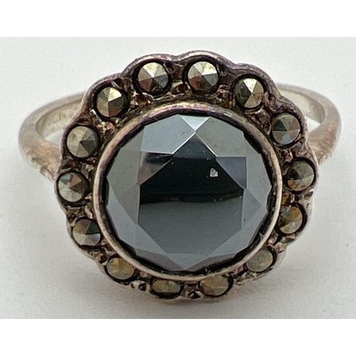 1056 - A vintage silver dress ring set with a central round cut hematite stone, surrounded by 14 marcasite ... 