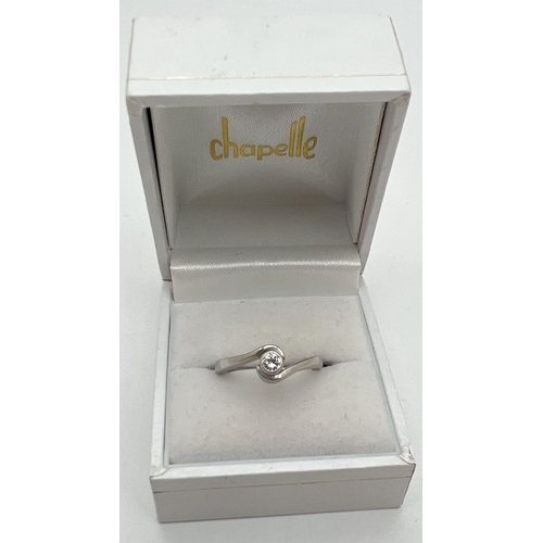 1057 - A boxed twist design platinum .10ct diamond solitaire ring by Chapelle. Tests as platinum, shows sig... 