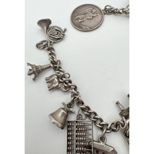 1058 - A vintage white metal curb chain bracelet with 15 silver and white metal charms. No clasp to bracele... 