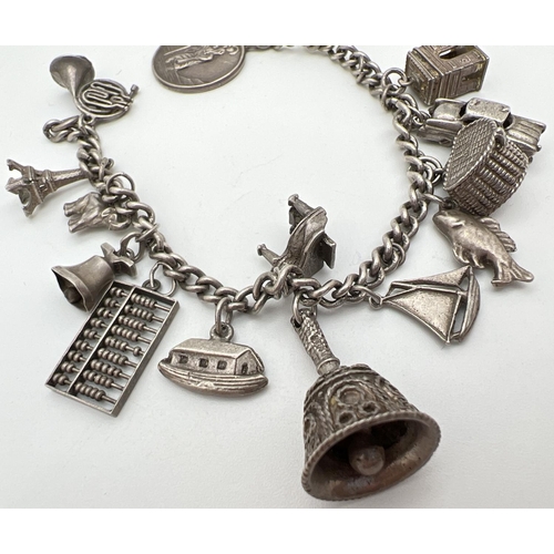 1058 - A vintage white metal curb chain bracelet with 15 silver and white metal charms. No clasp to bracele... 