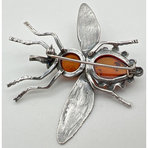 1059 - A white metal amber set brooch/pendant in the shape of a flying insect. Body set with a round and te... 