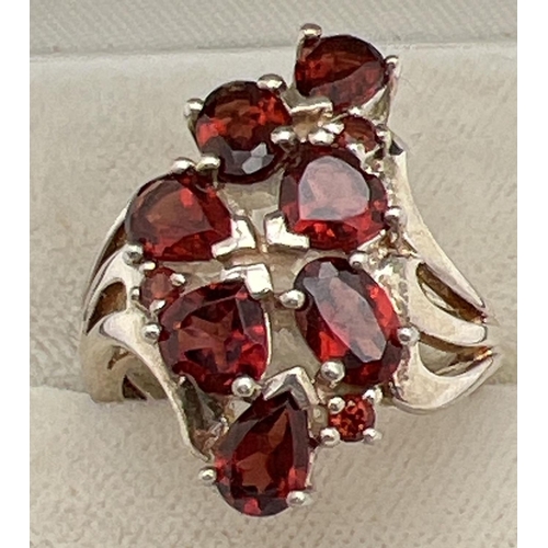 1060 - A silver statement dress ring set with teardrop, round, oval and heart shaped garnet stones. Swirl d... 