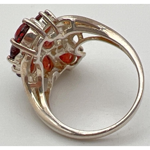 1060 - A silver statement dress ring set with teardrop, round, oval and heart shaped garnet stones. Swirl d... 